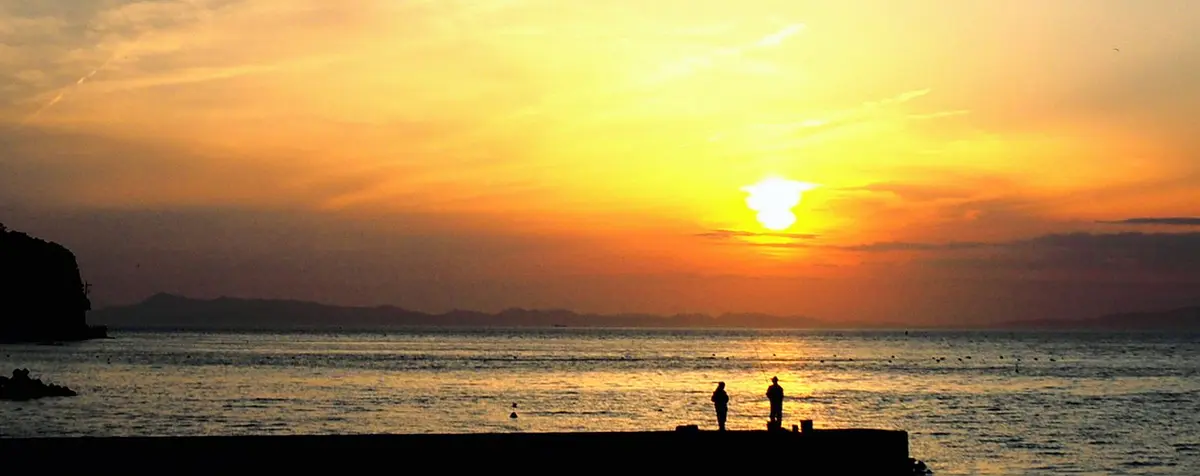 岬町の海に沈む夕日と漁港の風景